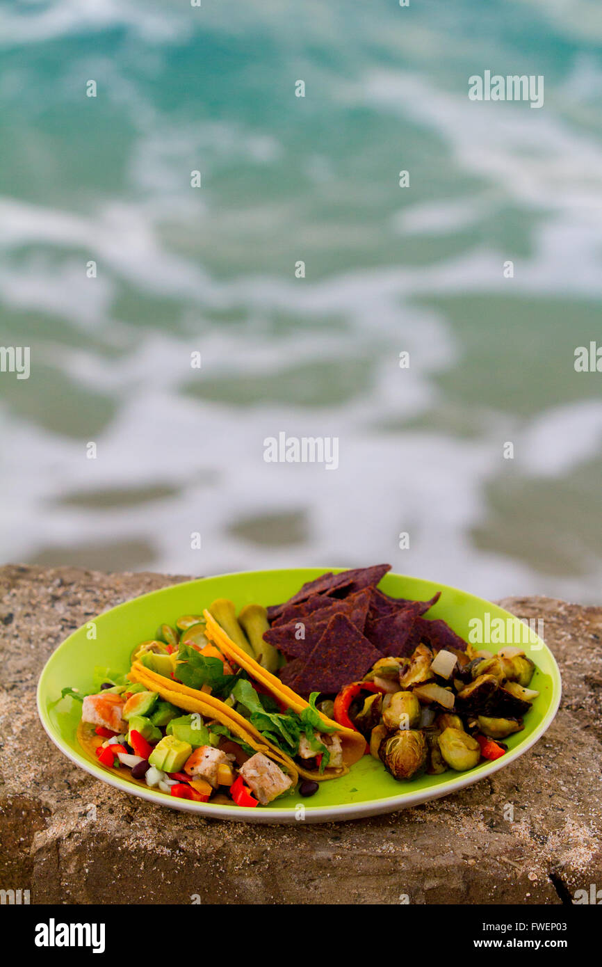 Diese einfache Mahlzeit Fischtacos serviert mit gebratenem Gemüse und Chips auf eine grüne Platte in Hawaii. Stockfoto