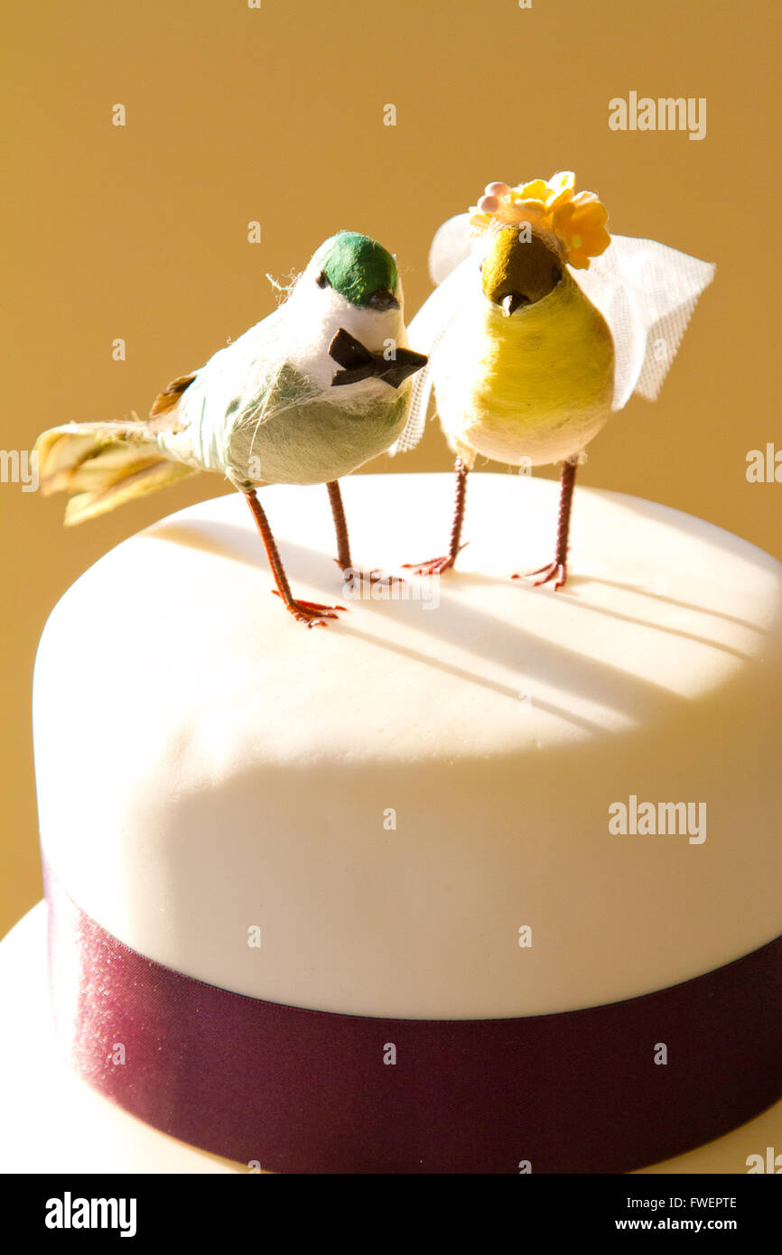 Eine traditionelle weiße Hochzeitstorte ist garniert mit Handwerk Vögel und verpackt in lila Band an der Braut und des Bräutigams-Rezeption. Stockfoto