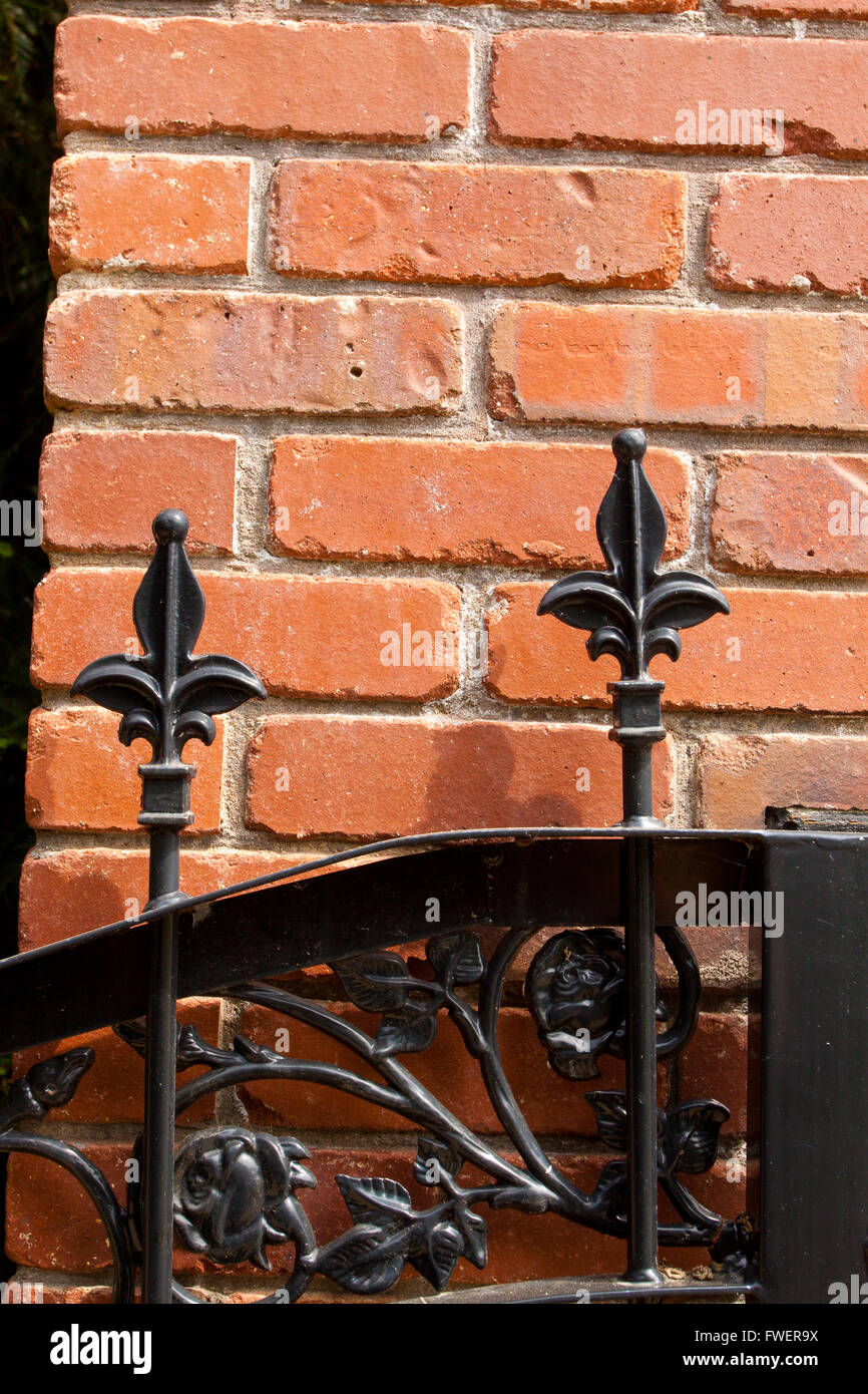 Eine schmiedeeiserne Metalltor mit Fleur de Lis Muster an der Spitze ist vor einer Wand in einem wohlhabenden Anwesen gebaut. Stockfoto