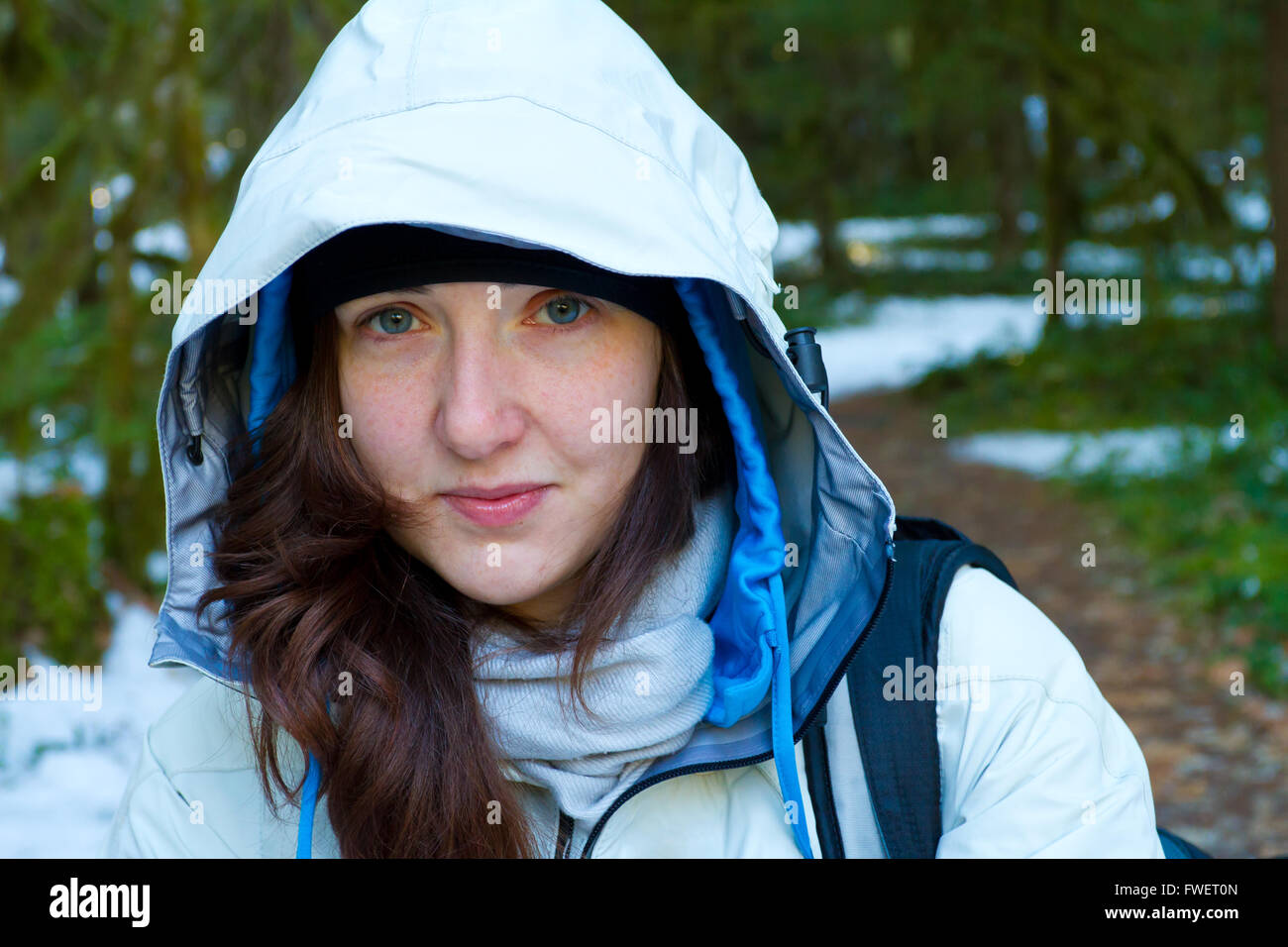 Eine Frau hält während ihrer Wanderung erholen und bis auf die Kamera zu schauen, während Sie trägt eine weiße Jacke. Stockfoto
