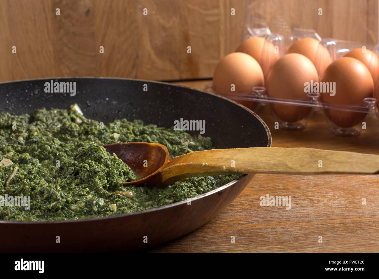 Brennnesseln mit Sahne-Sauce und Knoblauch in den Kochtopf mit Löffel auf rustikalen Hintergrund gedünstet Stockfoto