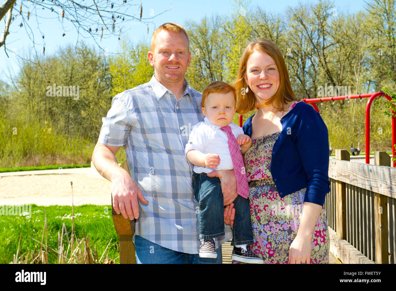 Ein Mann und eine Frau festhalten ihr Baby ein Jahr alt Sohn und posieren für ein Familienfoto im Freien. Stockfoto