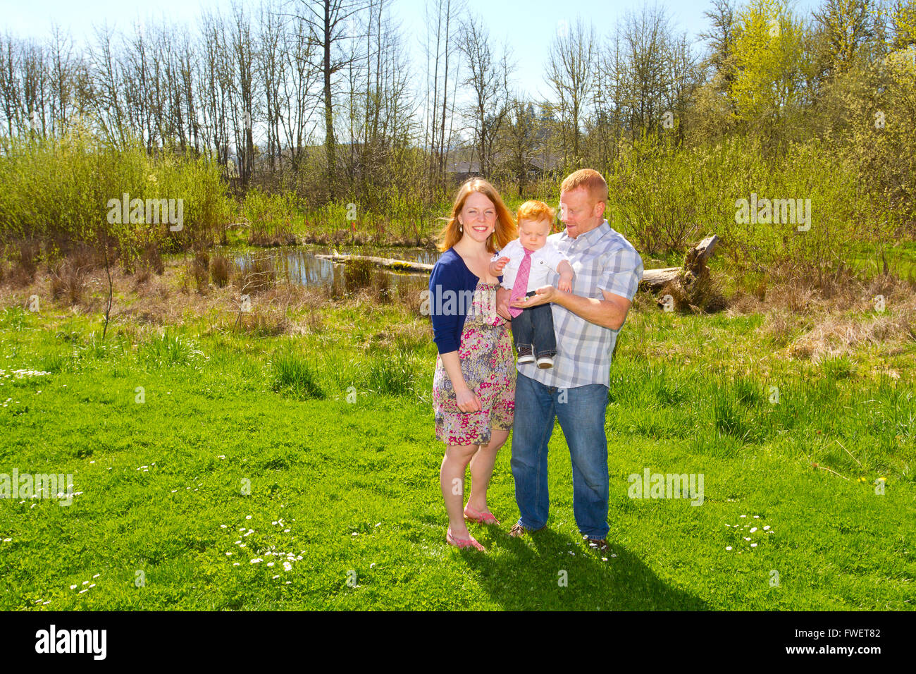 Eine Mama und Papa mit ihren einjährigen Baby in einem schönen Park, trendige Kleidung zu tragen. Stockfoto