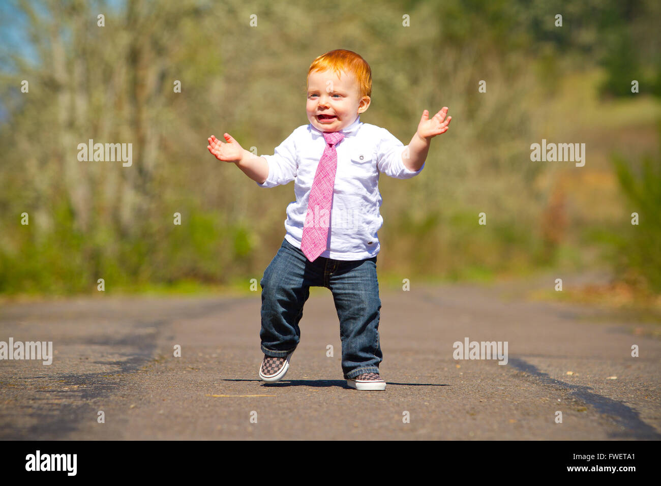 Ein einjähriger Junge dabei einige der seine ersten Schritte im Freien auf einem Pfad mit selektiven Fokus während des Tragens ein schönes Hemd und eine neckt Stockfoto