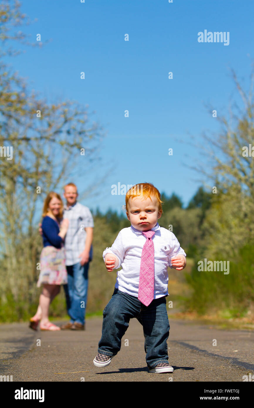 Eltern sind in diesem selektiven Fokus Bild unscharf, während ein Baby Boy in Richtung der Kamera ausgeführt wird. Stockfoto
