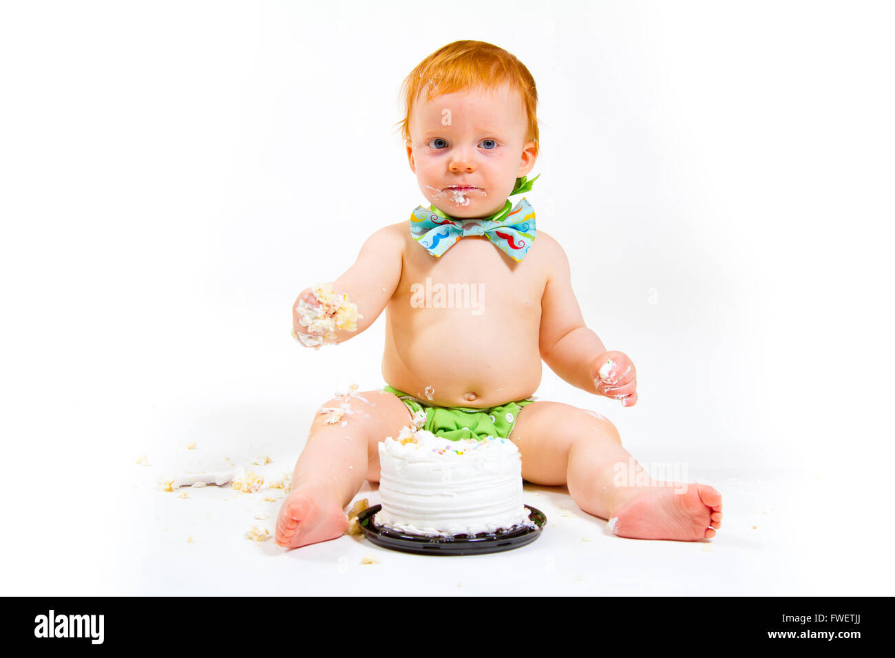 Ein Baby bekommt, Kuchen zum ersten Mal an seinem ersten Geburtstag in diesem Kuchen smash im Studio vor einem weißen Hintergrund zu essen. Stockfoto