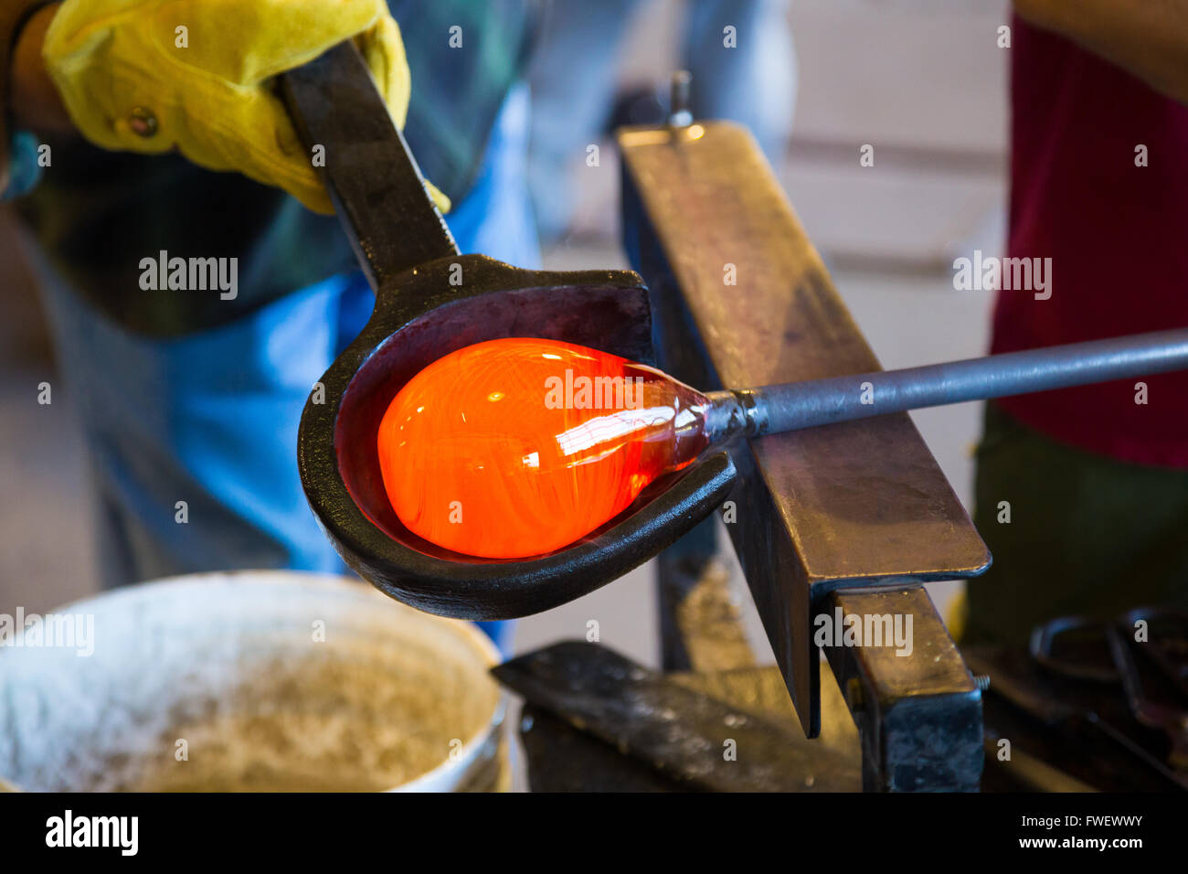 Ein sehr talentierter Glasbläser ist Bildung und Gestaltung Glas in einem Studio für Glasherstellung. Er schafft eine geriffelte Schale aus diesem pi Stockfoto