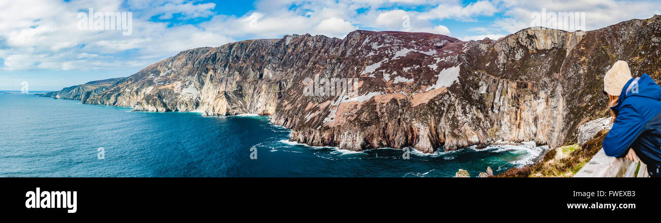 Eine Frau schaut auf Slieve League Klippen, Donegal, Irland, den höchsten Seeklippen in Irland. Stockfoto