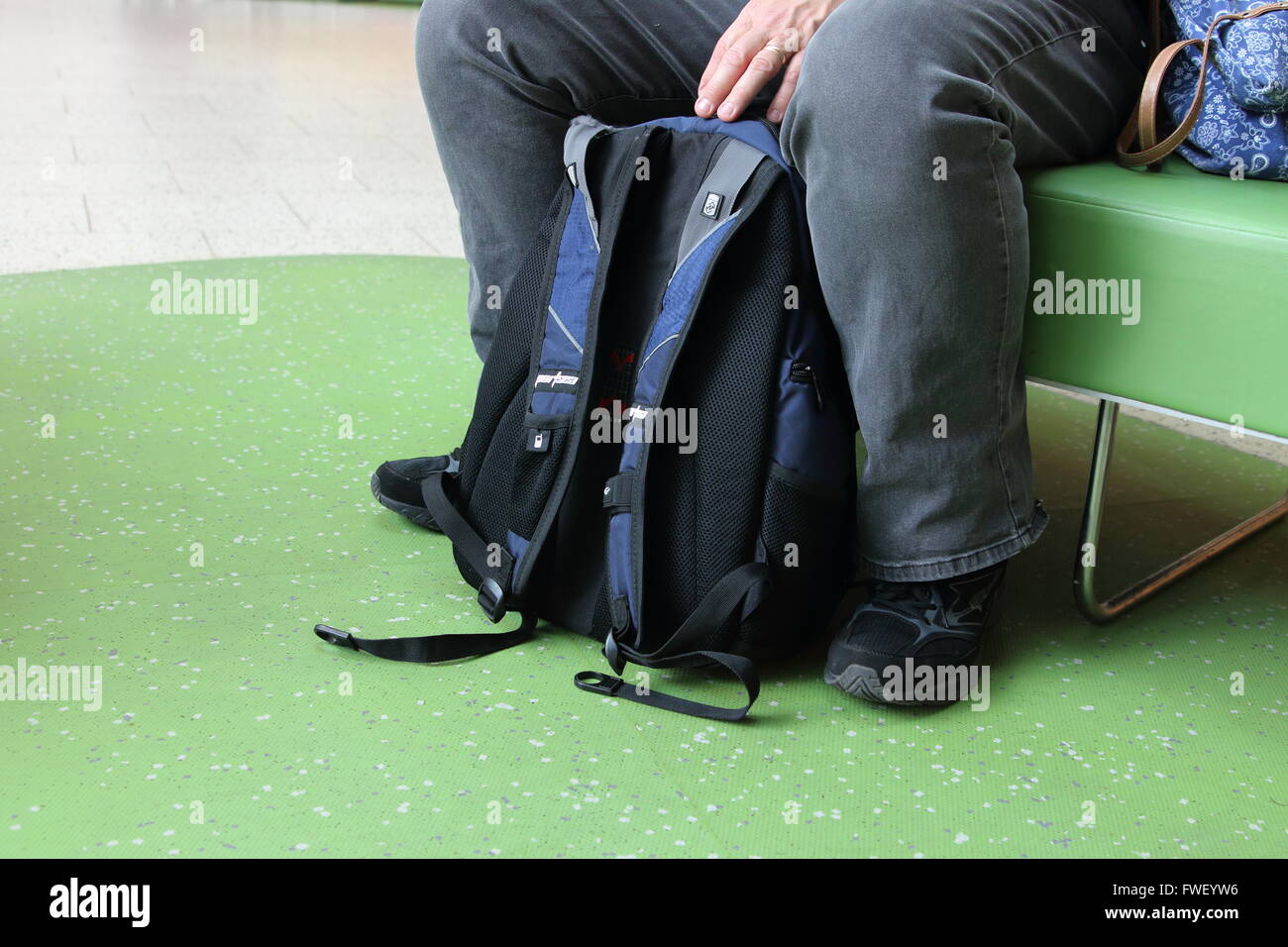 Männlichen Reisenden sitzen auf einer Bank mit einem Rucksack auf dem Boden Stockfoto