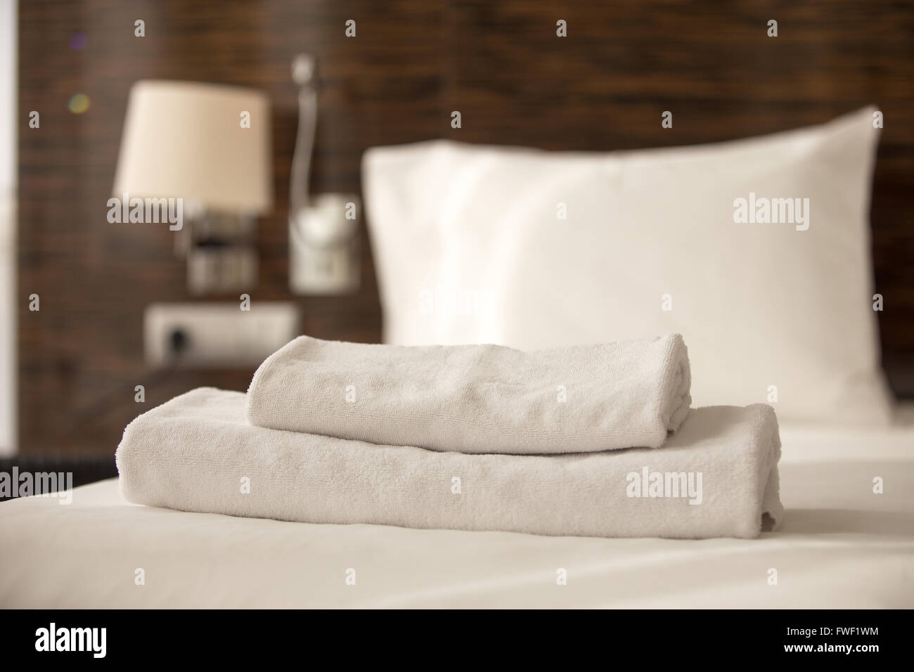 Gestapelte sauberen weißen Badetücher auf die Bettlaken im Hotelzimmer, Nahaufnahme Stockfoto