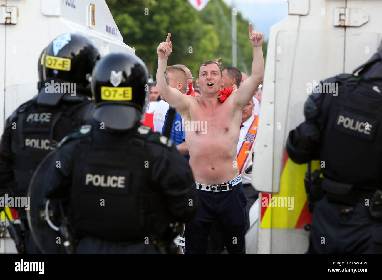 Bewaffnete Polizisten beobachten Loyalisten während der Schwierigkeiten im Norden Belfast nach einem anhaltenden Angriff auf Polizei im Bereich Woodvale Stockfoto