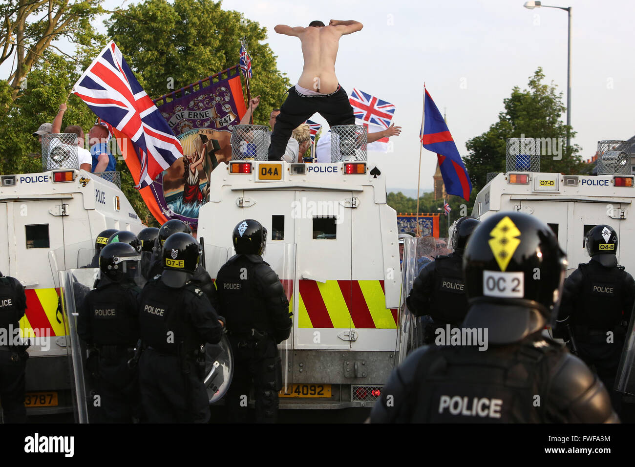 Bewaffnete Polizisten beobachten Loyalisten während der Schwierigkeiten im Norden Belfast nach einem anhaltenden Angriff auf Polizei im Bereich Woodvale Stockfoto