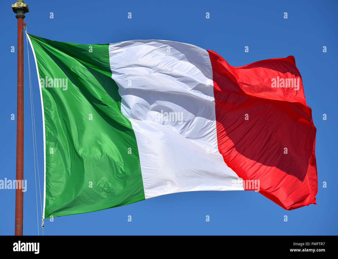 Italienische Fahne flattert im Wind, mit blauem Himmel. Grün, weiß, rot und Azure sind die italienischen Nationalfarben. Stockfoto
