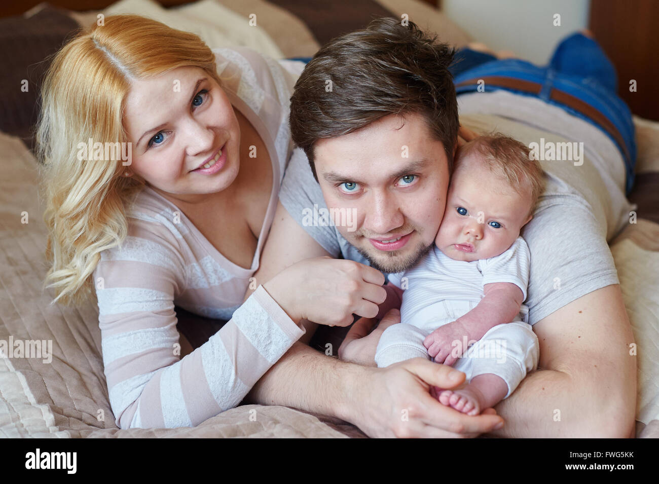 Mama und Papa spielt mit seinem kleinen Sohn auf dem Bett. Glückliche Familien-Konzept Stockfoto