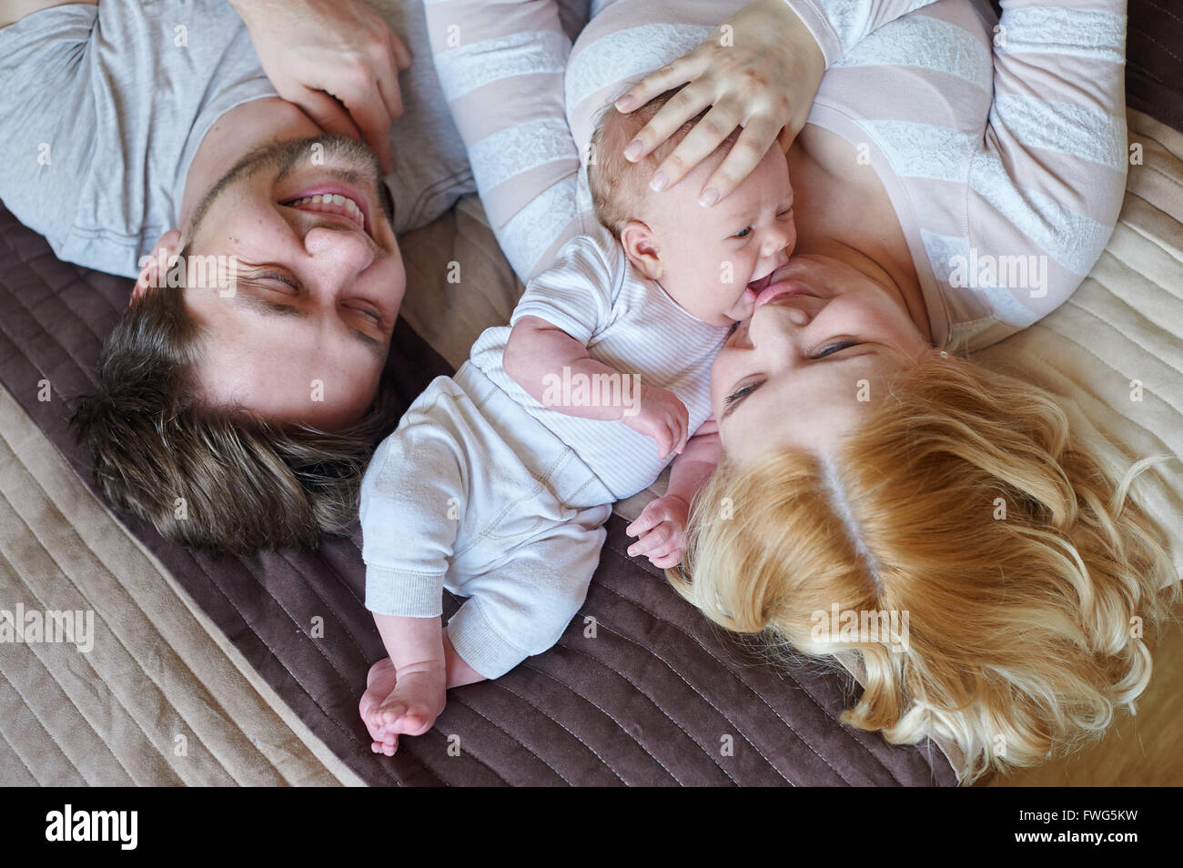Mama und Papa spielt mit seinem kleinen Sohn auf dem Bett. Glückliche Familien-Konzept Stockfoto