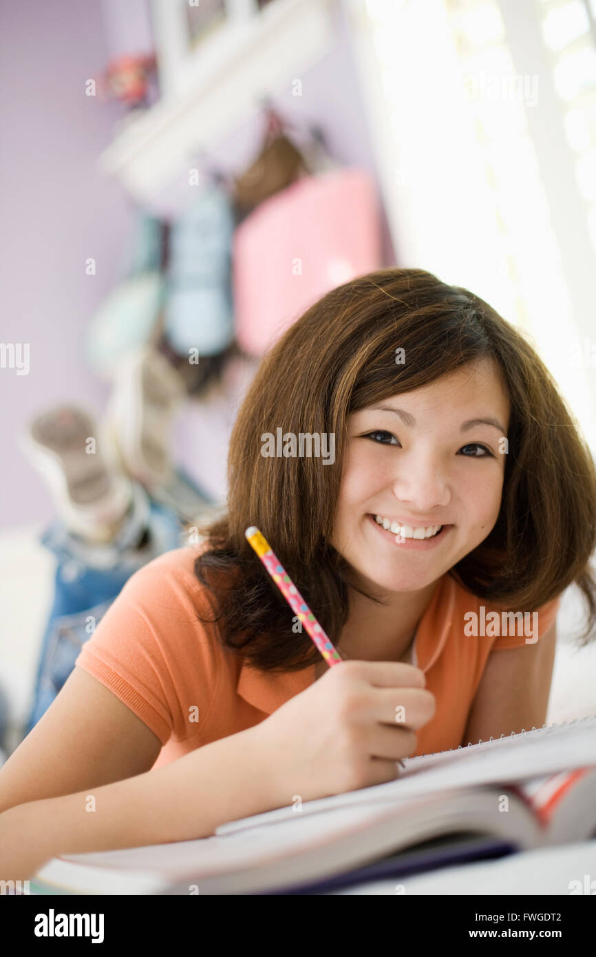 Ein Mädchen liegt auf ihrem Bett hält einen Stift und Notizbuch. Stockfoto