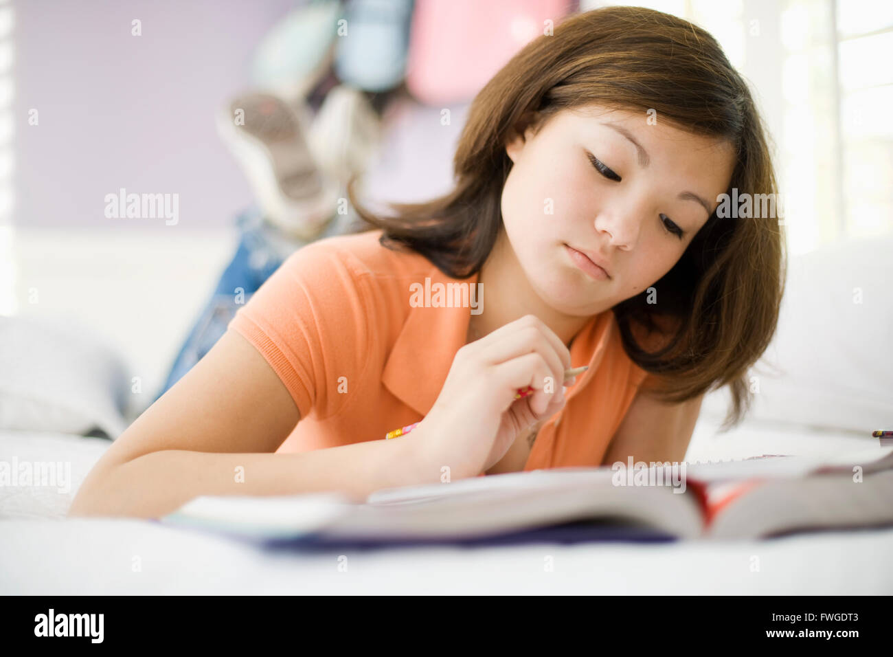 Ein Mädchen liegt auf ihrem Bett und las ein Buch. Stockfoto