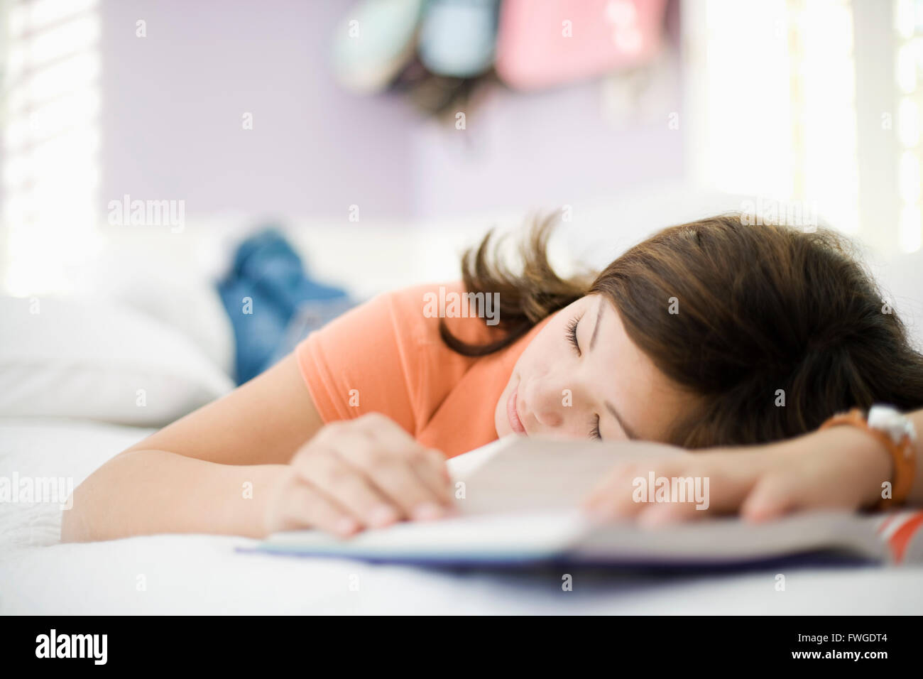 Ein Mädchen liegt auf ihrem Bett schlafen mit dem Kopf in ihren Schulbüchern. Stockfoto
