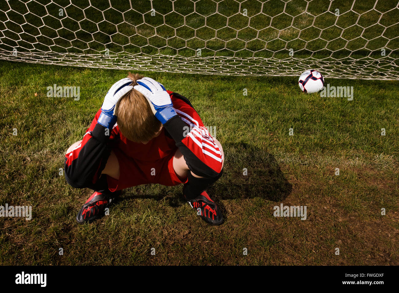 Ein Torwart mit dem Kopf in seine Hände und einem Fußball auf der Rückseite das Ziel netto. Stockfoto