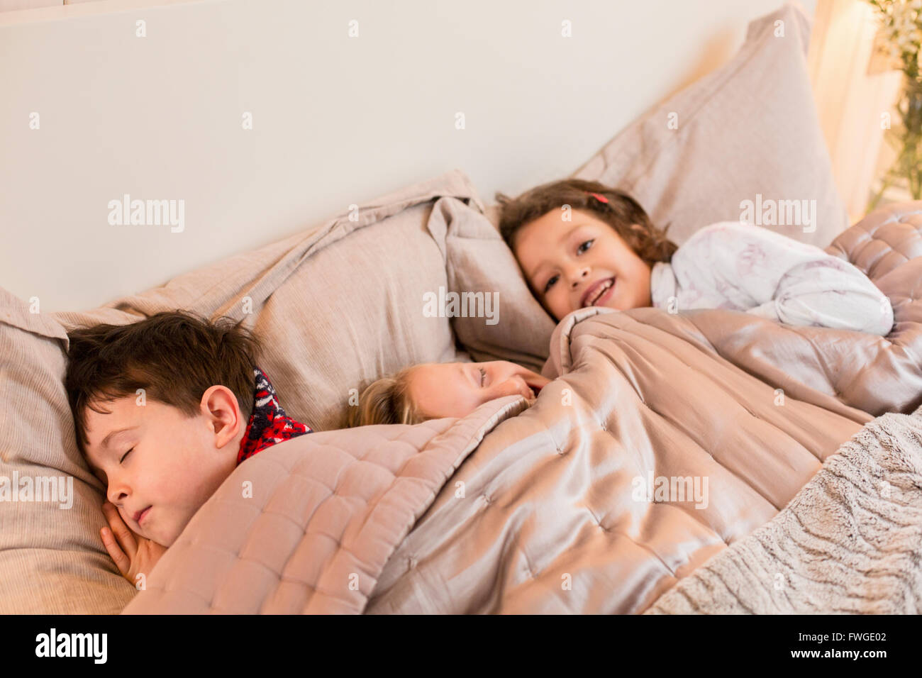 Drei Kinder in einem Bett unter der Decke liegen. Stockfoto