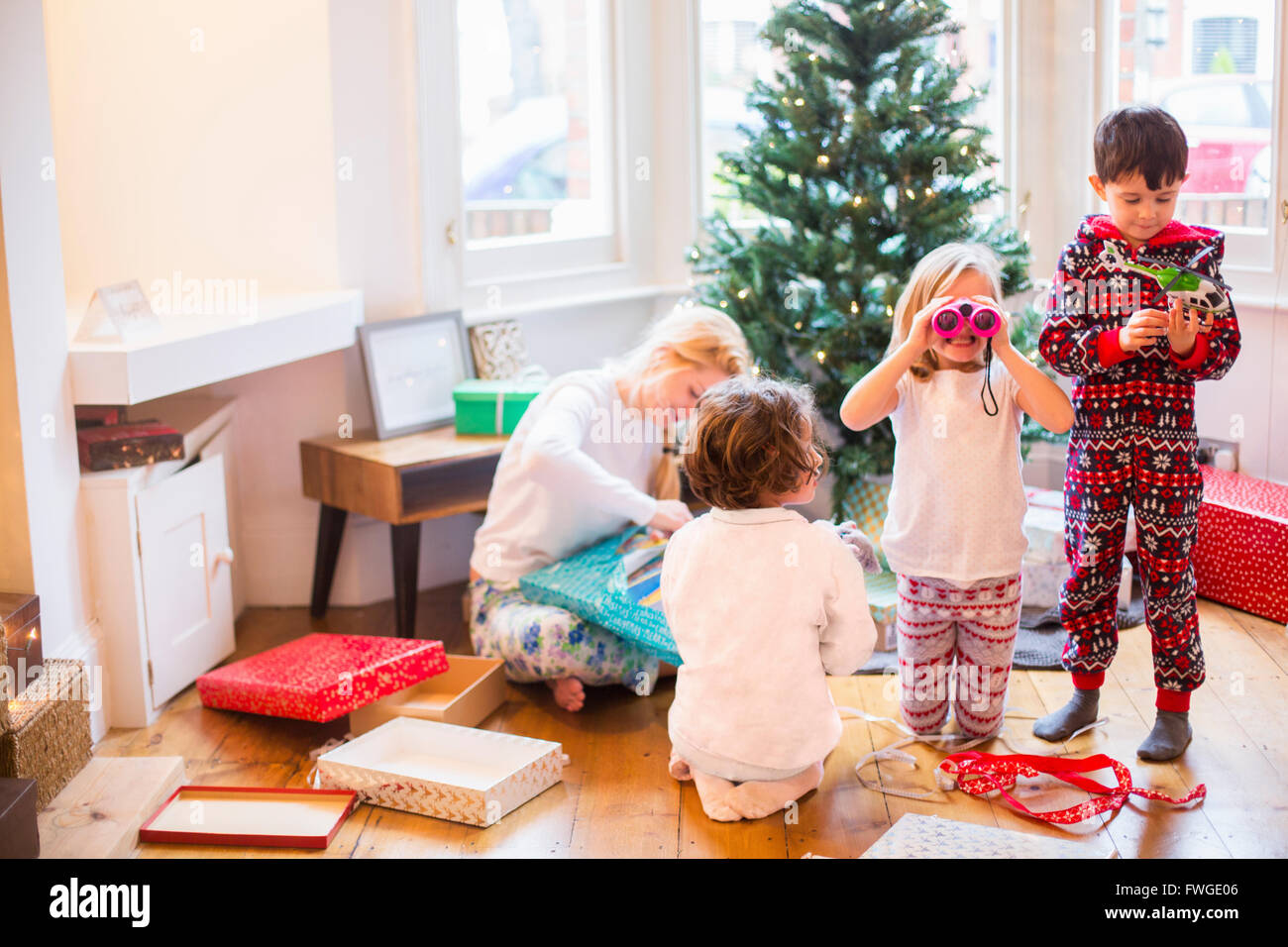 Eine Mutter mit drei Kindern am Weihnachtsmorgen Eröffnung präsentiert. Stockfoto
