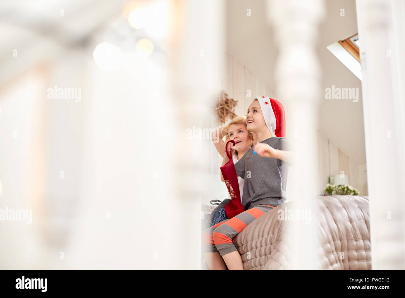 Zwei Kinder, einen jungen und Mädchen gesehen durch ein Schlafzimmer Tür, blickte aufgeregt: aufwachen am Weihnachtsmorgen. Stockfoto