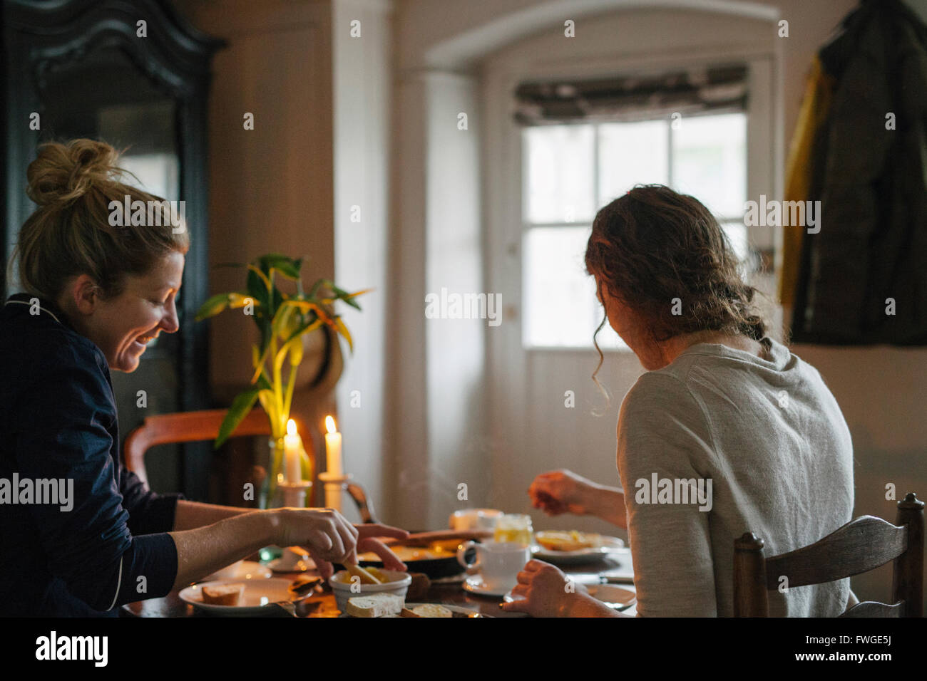 Zwei Frauen sitzen an einem Tisch mit einem Essen bei Kerzenschein. Stockfoto
