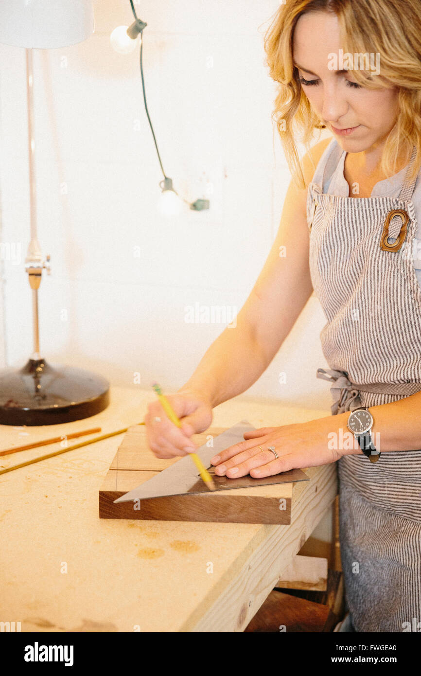 Eine Frau in ihrem Atelier mit einer Vorlage, hölzerne Blöcke markieren. Stockfoto