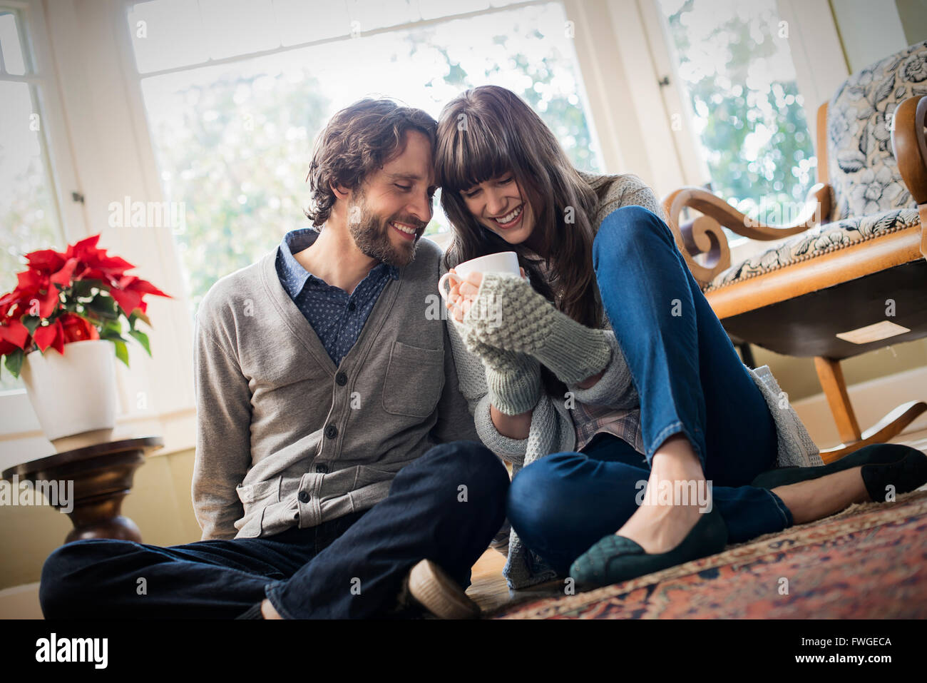 Ein paar, Mann und Frau sitzen dicht beieinander mit ihren Händen um Tassen Aufwärmen. Stockfoto