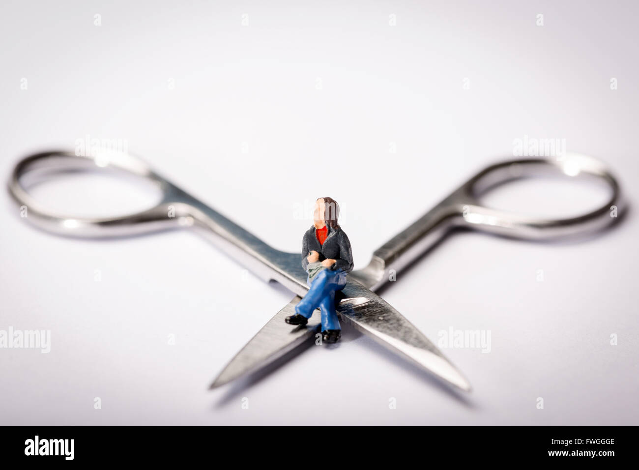 Vasektomie-Konzept-Bild einer Miniatur Figur Schneidersitz saß auf der Schere Stockfoto