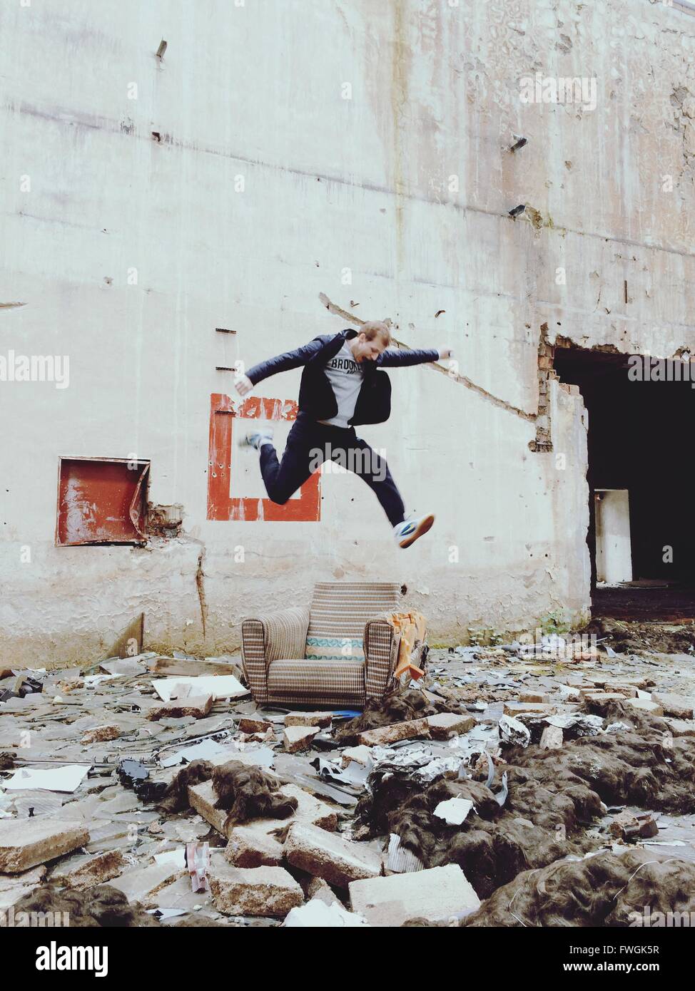 Junger Mann springt über Stuhl außerhalb verlassenen Gebäude Stockfoto