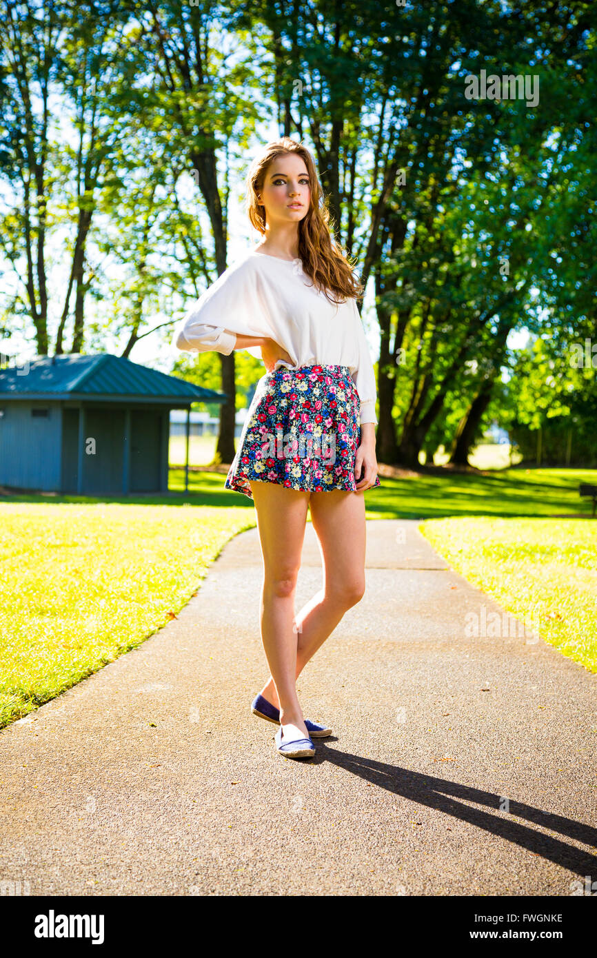 Ein schönes junges Mädchen posiert für ein Mode-Stil-Porträt im Freien in einem Park mit natürlichem Licht. Stockfoto