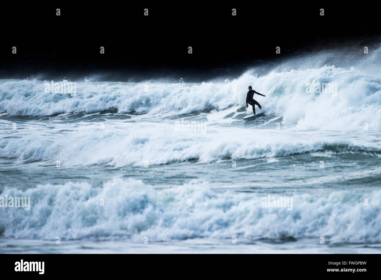 Ein Surfer in einer spektakulären Aktion auf den Fistral in Newquay, Cornwall, England. Stockfoto