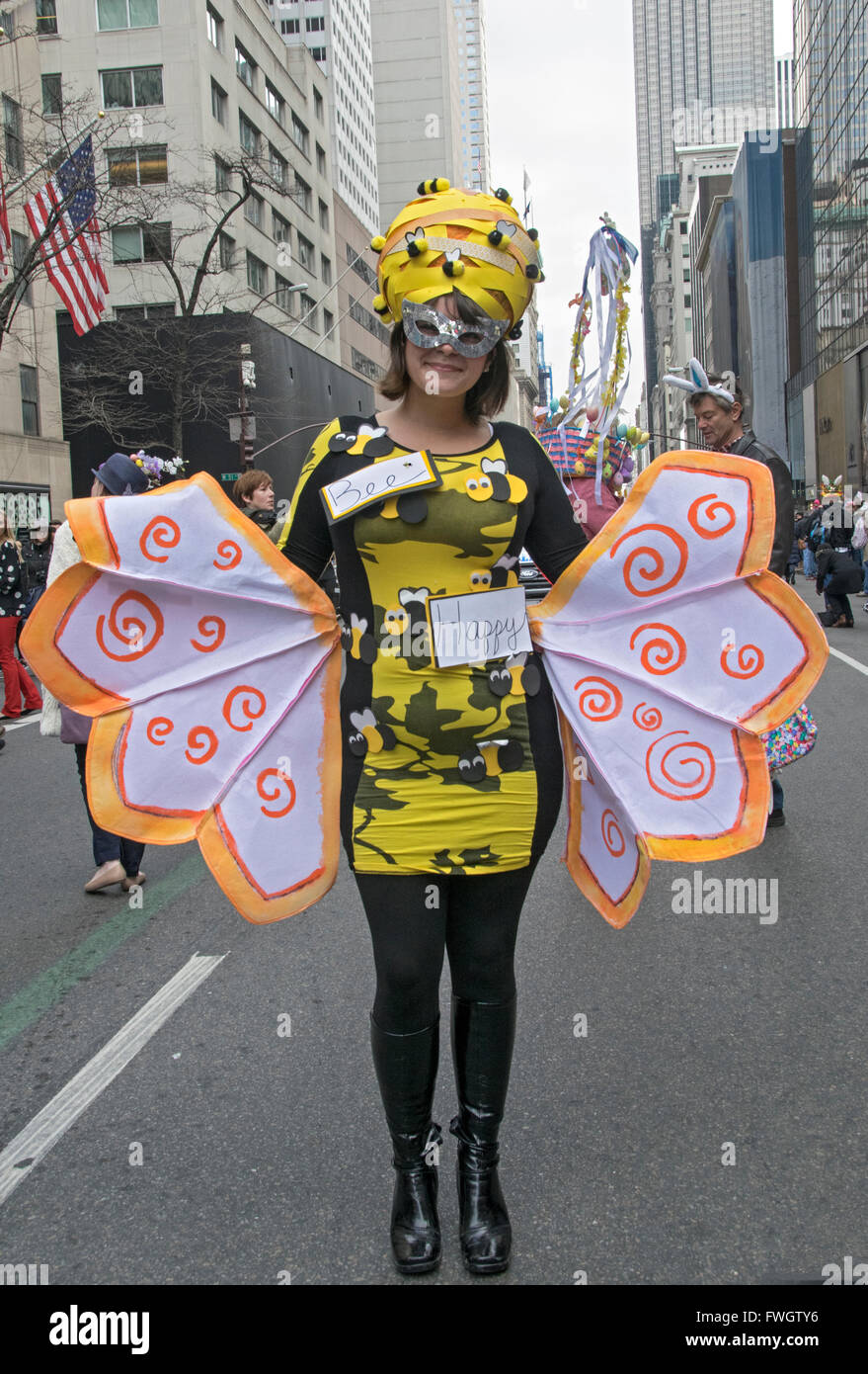 Eine Frau gekleidet wie eine Biene mit einem glücklich sein Schild auf der Fifth Avenue in Midtown Manhattan, New York City an der Easter Parade. Stockfoto