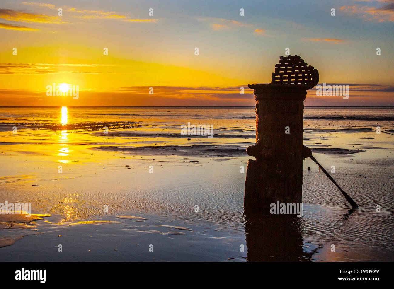Sonnenuntergang und Strand Landschaft Southport, Merseyside, UK. 5. April 2016. UK Wetter. Dramatischer Sonnenuntergang über der Irischen See Ausleuchten der 'Liverpool Fleetwood viktorianische gusseiserne Gezeiten Standard bei niedrigem Wasserstand. Die römischen Ziffern empfehlen es für ein Schiff Entwurf Markierungen in vergangenen Zeiten Kennzeichnung einen Kanal für den Zugang zu den inzwischen aufgelösten bezieht, und versandete der Hafen. Stockfoto
