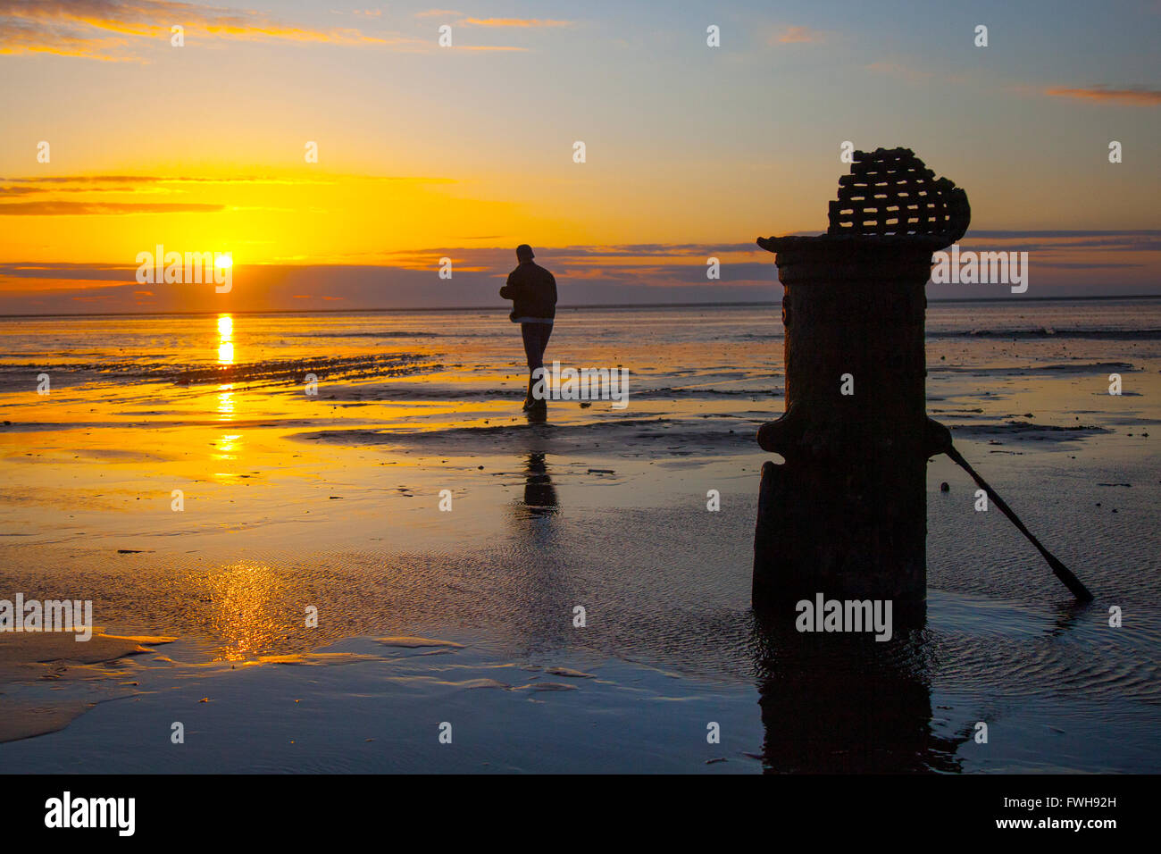 Sonnenuntergang und Strand Landschaft Southport, Merseyside, UK. 5. April 2016. UK Wetter. Dramatischer Sonnenuntergang über der Irischen See Ausleuchten der 'Liverpool Fleetwood viktorianische gusseiserne Gezeiten Standard bei niedrigem Wasserstand. Die römischen Ziffern empfehlen es für ein Schiff Entwurf Markierungen in vergangenen Zeiten Kennzeichnung einen Kanal für den Zugang zu den inzwischen aufgelösten bezieht, und versandete der Hafen. Stockfoto