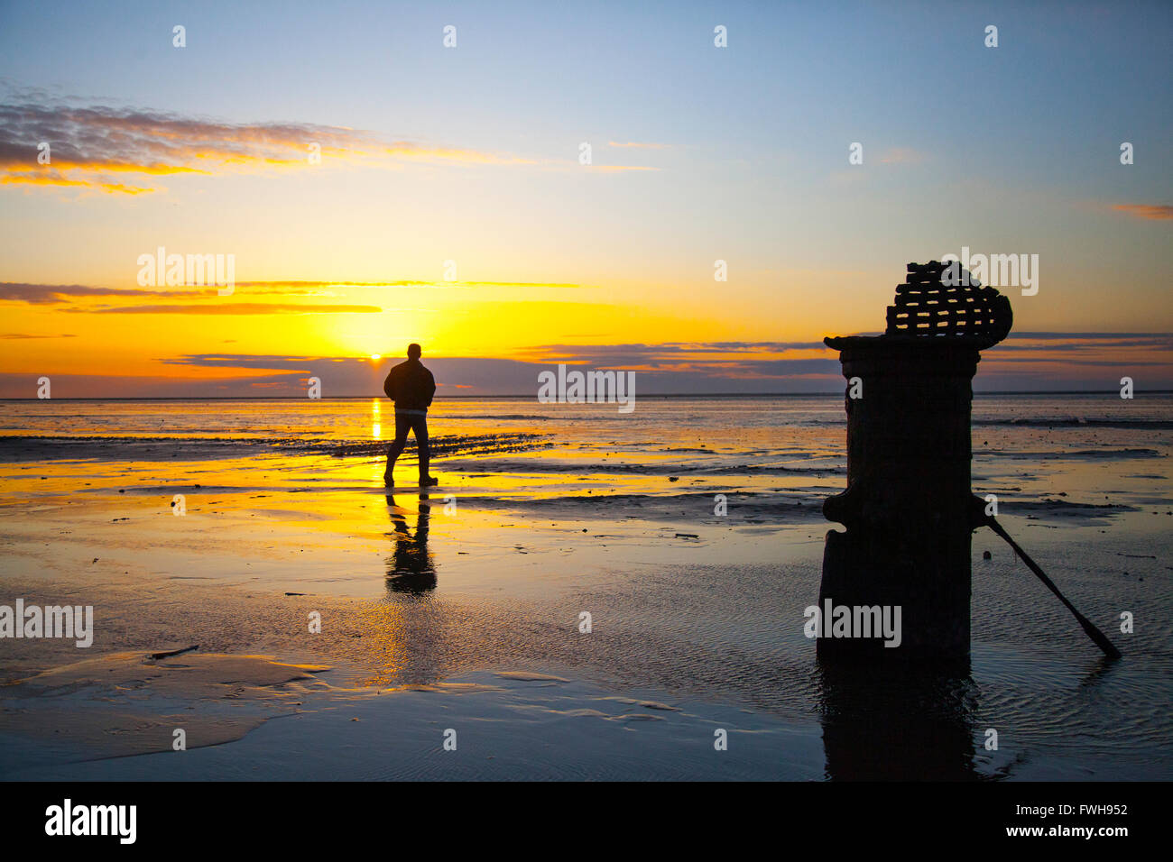 Sonnenuntergang und Strand Landschaft Southport, Merseyside, UK. 5. April 2016. UK Wetter. Dramatischer Sonnenuntergang über der Irischen See Ausleuchten der 'Liverpool Fleetwood viktorianische gusseiserne Gezeiten Standard bei niedrigem Wasserstand. Die römischen Ziffern empfehlen es für ein Schiff Entwurf Markierungen in vergangenen Zeiten Kennzeichnung einen Kanal für den Zugang zu den inzwischen aufgelösten bezieht, und versandete der Hafen. Stockfoto