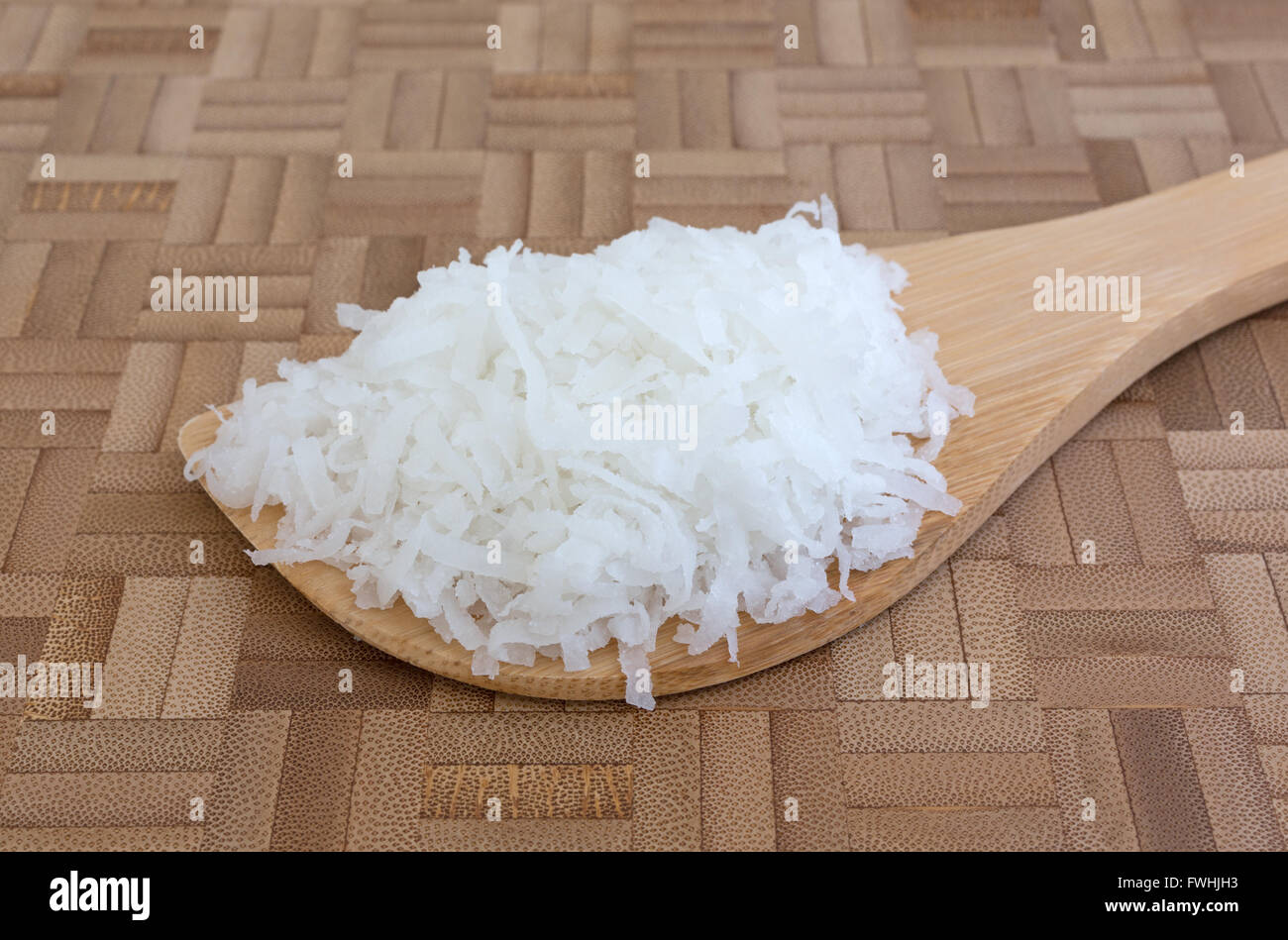 Seitenansicht eines Teils der gesüßte Kokosflocken auf einem Löffel auf ein Holz Schneidebrett. Stockfoto