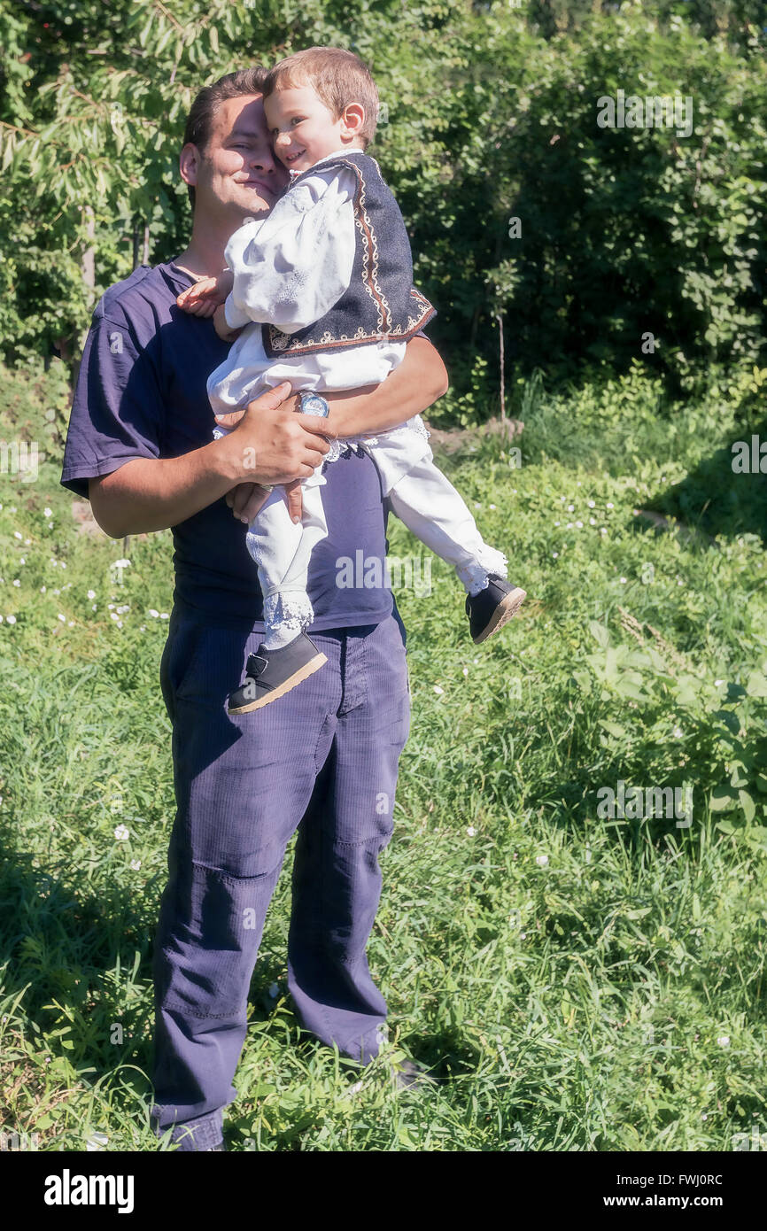 Glücklicher Junge gekleidet In eine traditionelle rumänische Tracht Held In den Armen seines Vaters Stockfoto