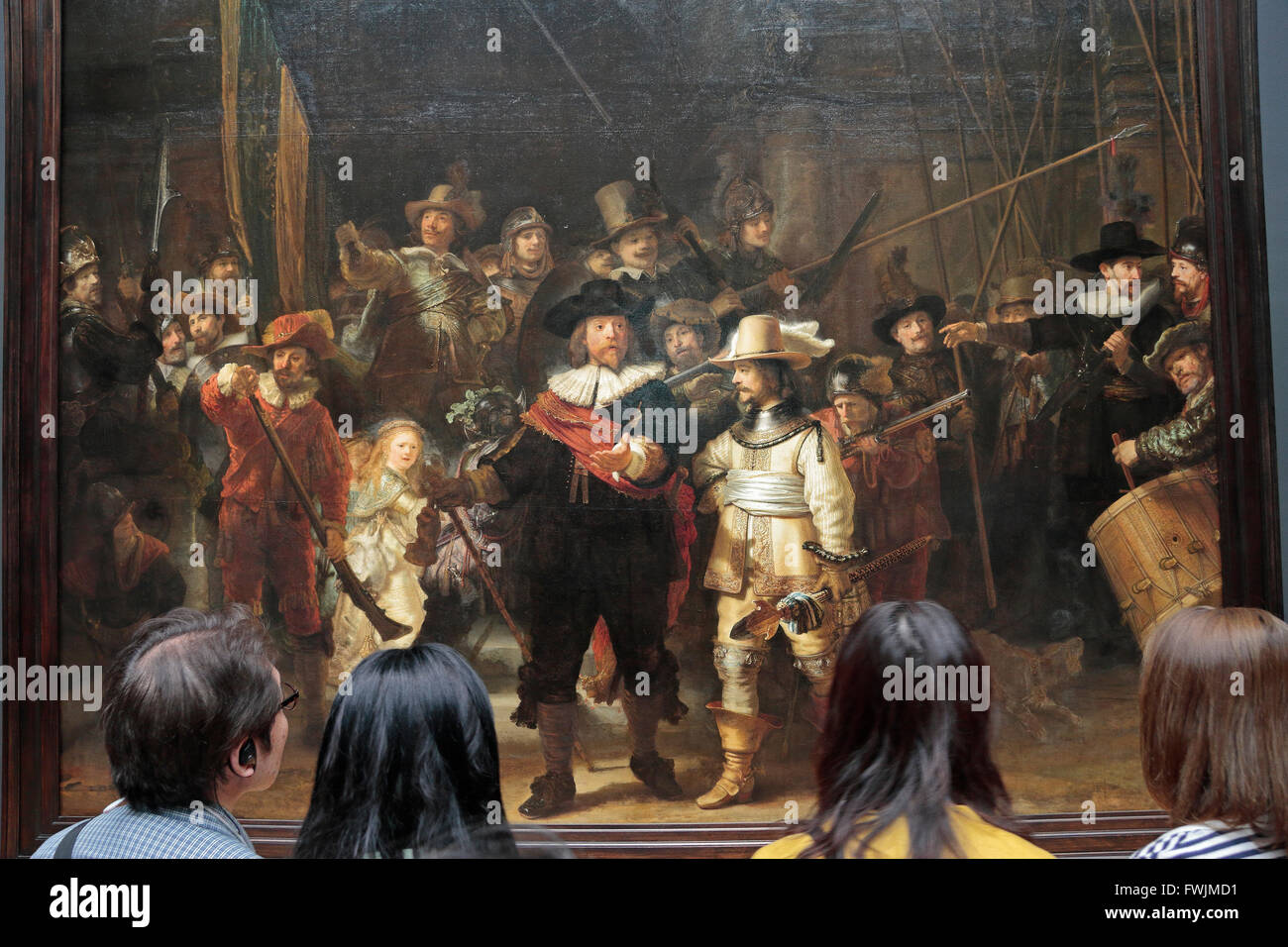 Besucher schauen Sie genau auf "die Nachtwache," (1642) von Rembrandt van Rijn im Rijksmuseum, Amsterdam, Niederlande. Stockfoto
