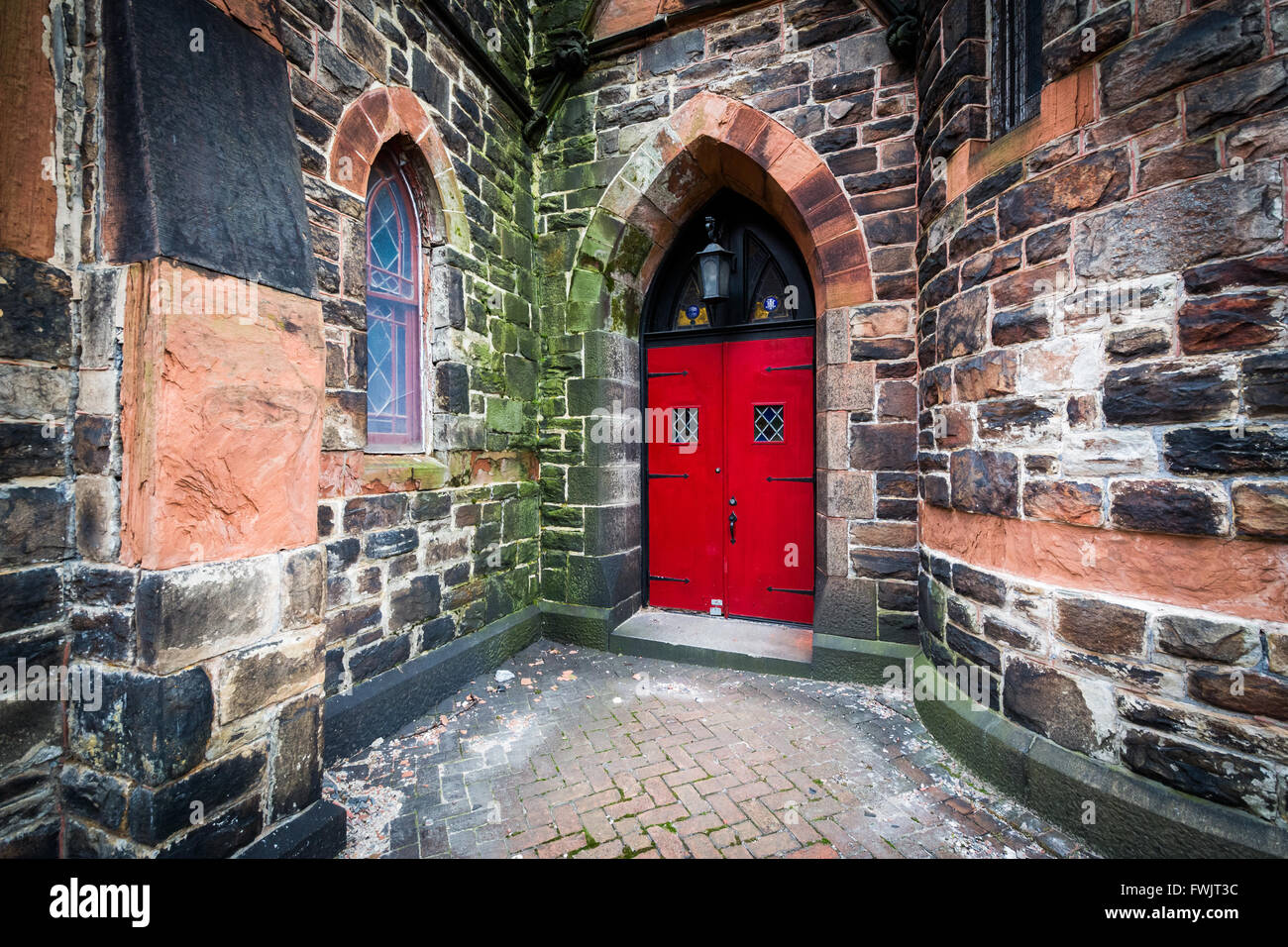 Rote Tür auf einer alten Steinkirche in Bolton Hill, Baltimore, Maryland. Stockfoto