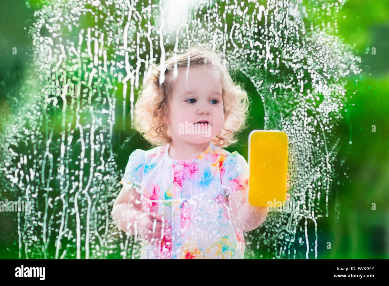 Kleines Mädchen waschen ein Fenster. Kinder das Haus zu reinigen. Kindern helfen zu Hause. Kleinkind Kind Reinigung von Fenstern und Türen Stockfoto