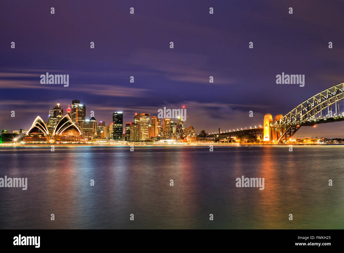 Panoramablick auf Sydney CBD Stadtbild bei Sonnenuntergang über noch verschwommen Wasser des Hafens mit Fragment des Hafens Brückenbogen. Stockfoto