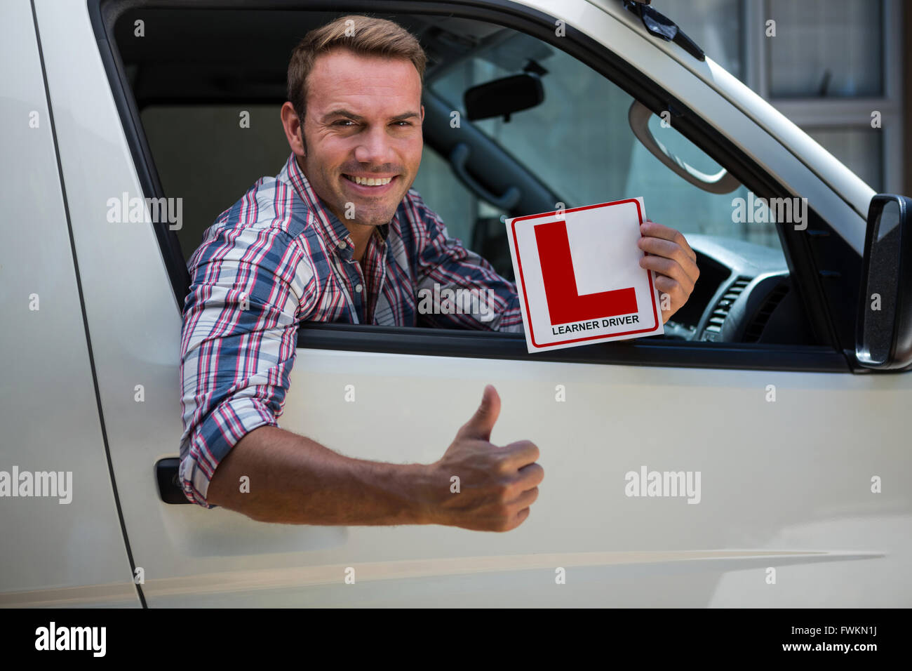 Junger Mann gestikulieren Daumen nach oben mit einem Lernenden Fahrer Schild Stockfoto