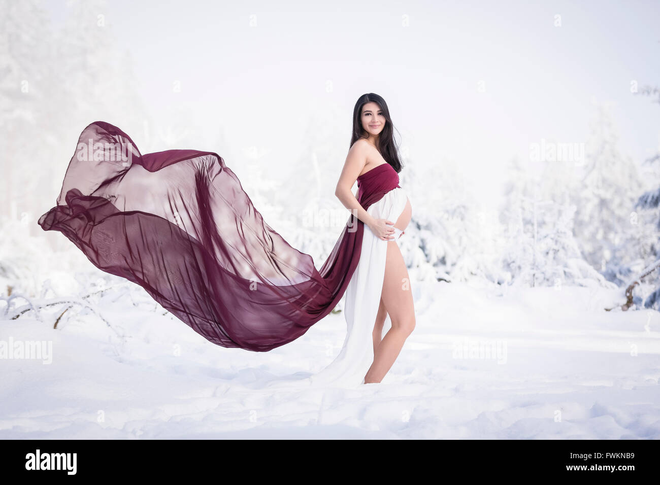 Schwangere Frau, die im Schnee Stockfoto