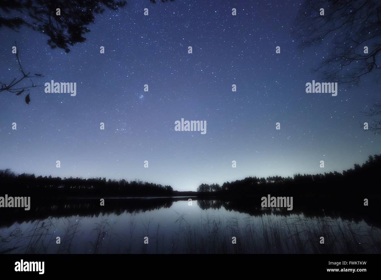 Ruhige Nachtszene mit Sternenhimmel an einem See in Finnland. Reflexion der Sterne auf das Stille Wasser des Sees. Stockfoto