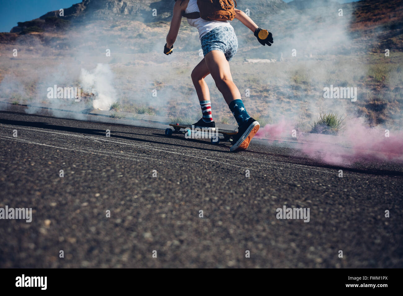 Bild der jungen Frau auf einer Straße skateboarding beschnitten. Skateboard Deck mit farbigen Rauchgranate. Stockfoto