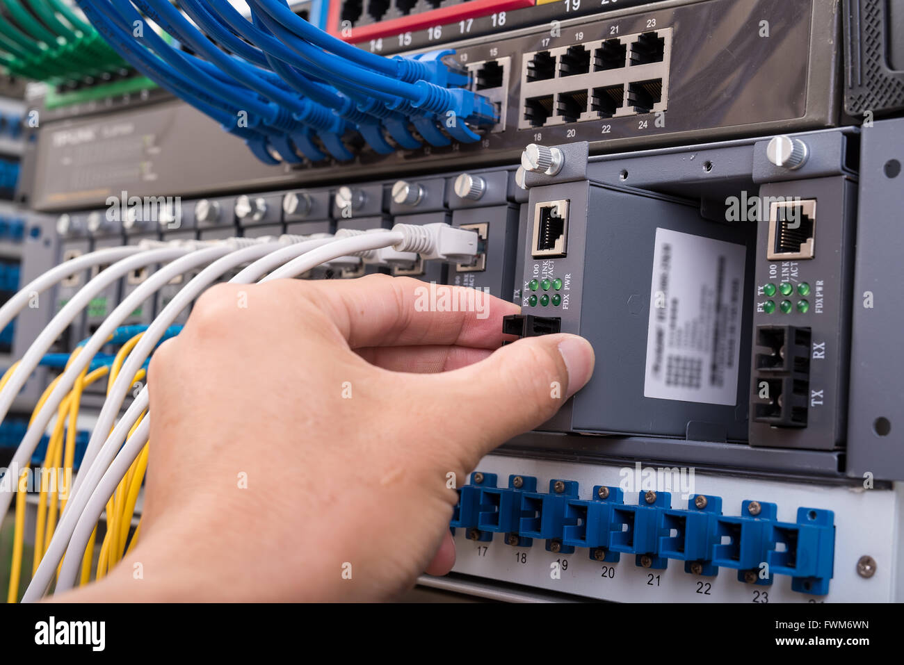 Mann bei der Arbeit im Netzwerk Server Zimmer mit LWL-Hub für die digitale Kommunikation und Internet Stockfoto