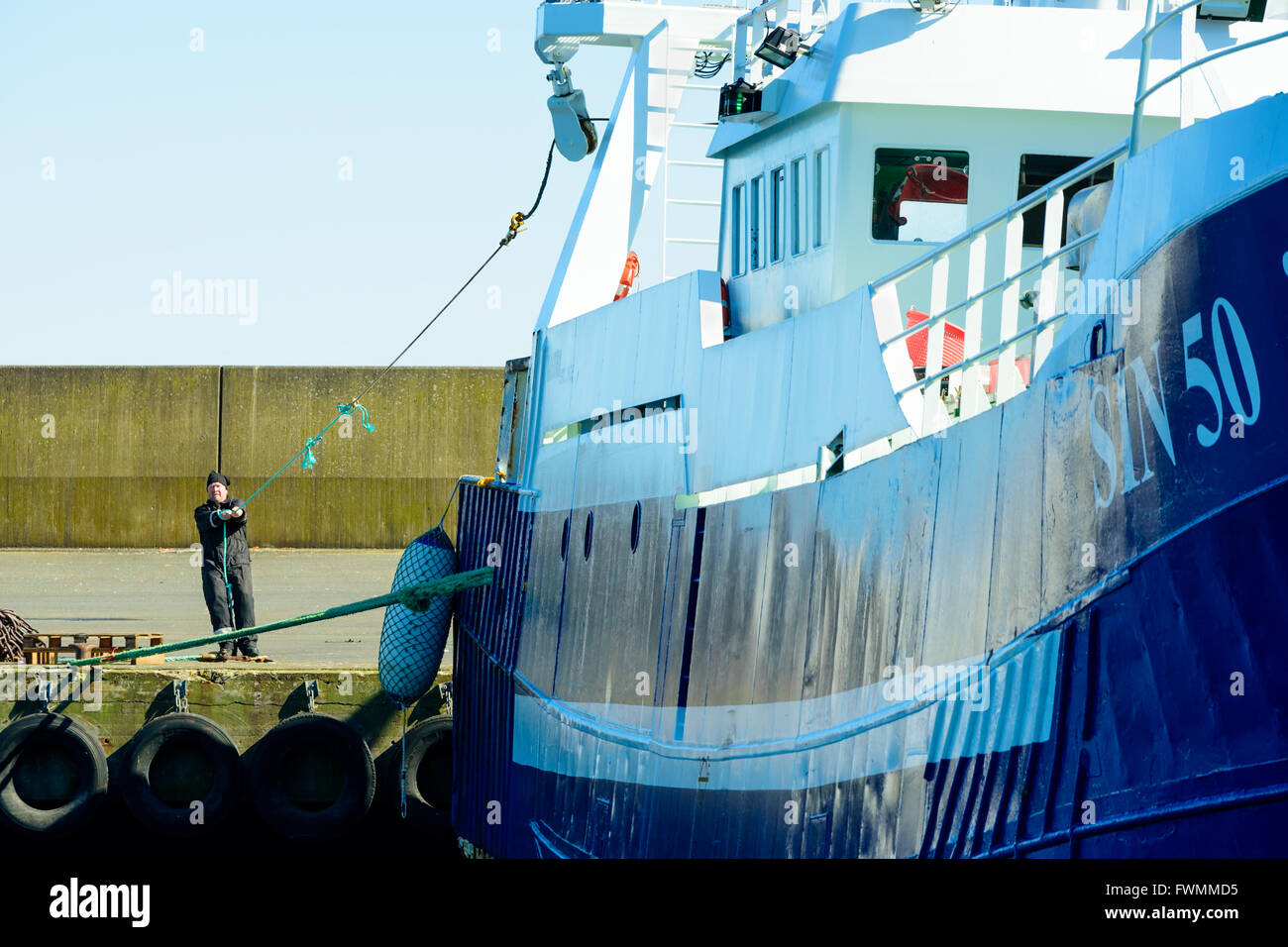 Simrishamn, Schweden - 1. April 2016: Eine Person auf Dockside ziehen an einem Seil von einem Fischerboot. Ein dünnes Seil wird verwendet, um eine Thic bekommen Stockfoto