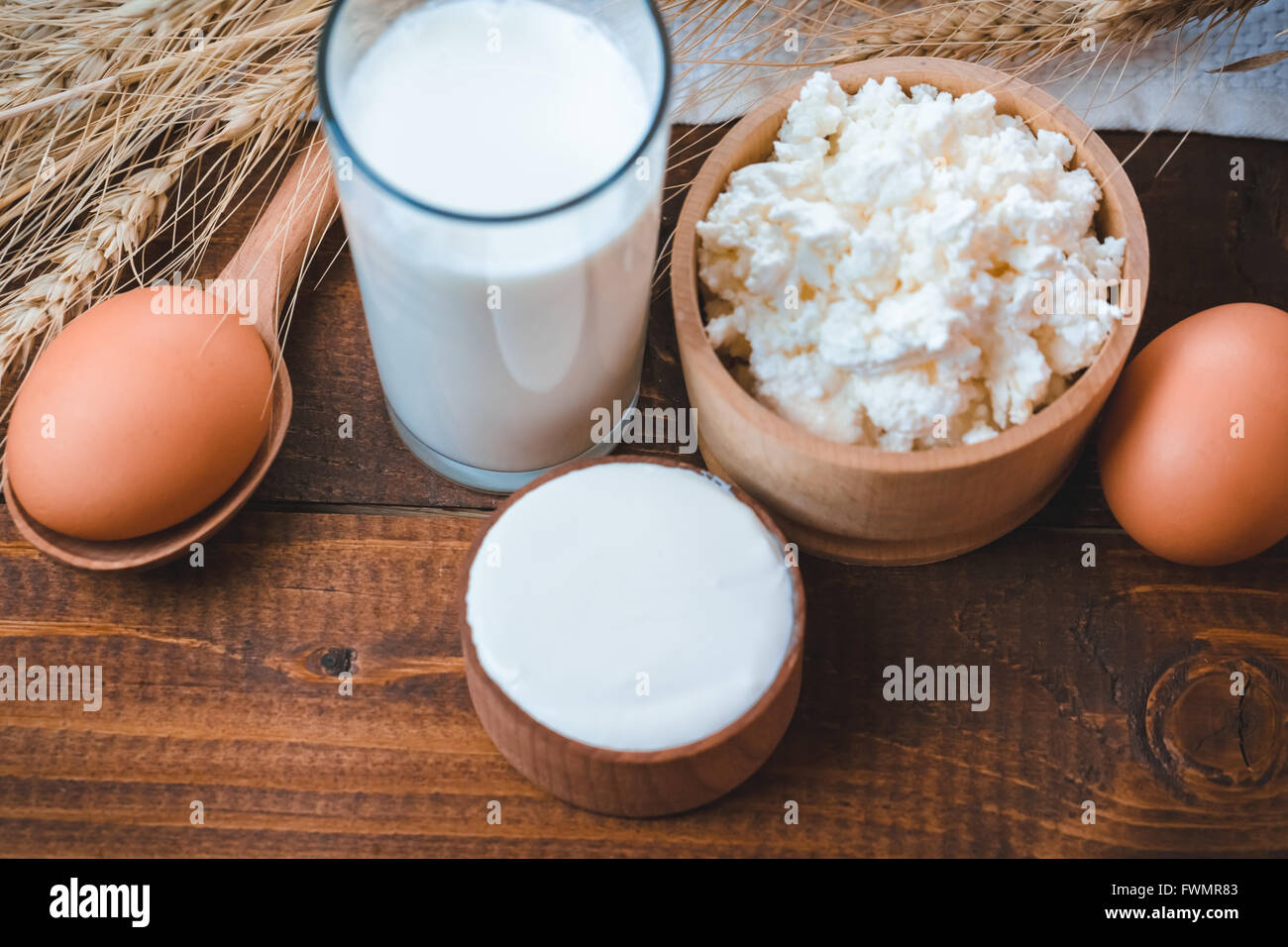 Natürliche selbstgemachte Produkte: Milch, Käse, Sauerrahm und Eiern auf den alten hölzernen Hintergrund mit Ähren. mit Platz für Ihre te Stockfoto